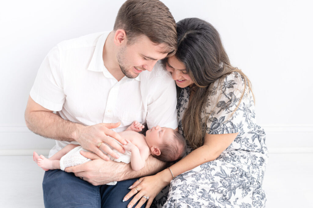New parents holding their newborn child for an in-studio newborn photo shoot
