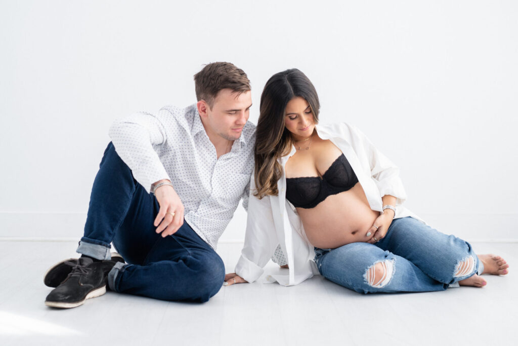 pregnant mother and male partner posing on floor for maternity photoshoot 